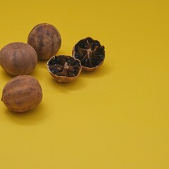 Sun dried organic Loomi or Black Lime, Black Lemon, Omani Lemon fruits on yellow background. Middle Eastern cuisine