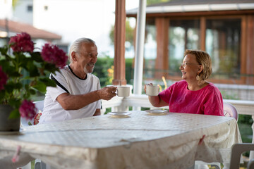 Retirement. Senior couple drinking coffee on porch in their house. Two mature man and woman drinking coffee and smiling or discussing plans for future.