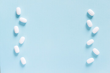 Scattered white pills on blue table. Mock up for special offers as advertising, web background or other ideas. Medical, pharmacy and healthcare concept. Copy space. Empty place for text or logo.