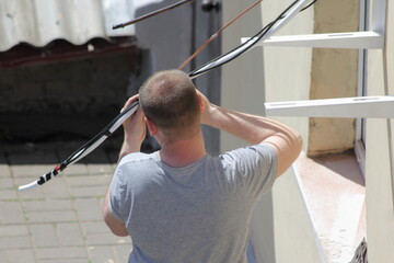 Serviceman installs air conditioner outdoor wall pipeline