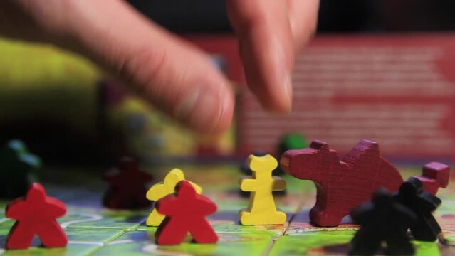 Board game carcasson with tiles and wooden playing pieces close-up.