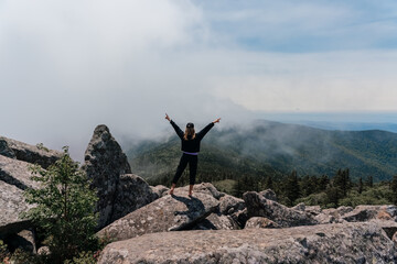 A girl on top of Mount Pidan looks at a beautiful mountain valley in the fog in summer. Travel and tourism. Hiking