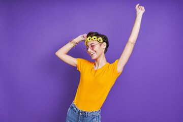Happy young woman with floral head wreath gesturing while standing against purple background