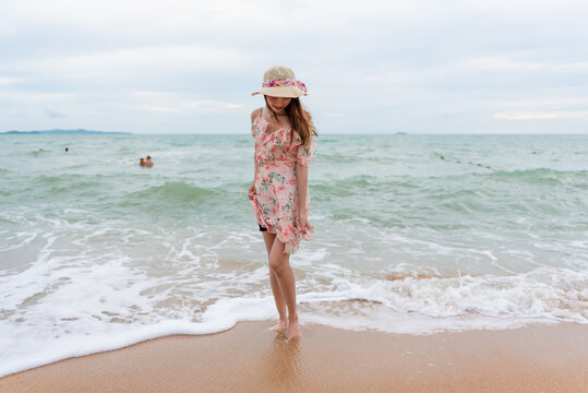 Young woman barefoot walking on the sand beach.