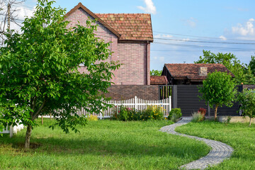 Stone path on a green lawn in front of brick houses