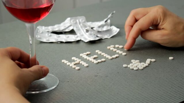 Pills on female hands. A woman with a mental disorder is about to commit suicide by poisoning herself with pills, folds the word Help from the pills. Overdose and suicide concept, suicide help. 
