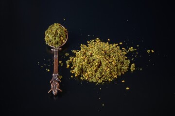 Zaatar or Zather is name of middle eastern spice herbal mix with sumac,thyme,oregano,bible hyssop and sesame seeds on black background in vintage oriental design spoon.Organic herbs and spices.