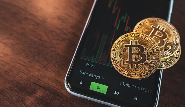 Bitcoin gold coin put on a black mobile telephone background with trading graph. Cryptocurrency concept.