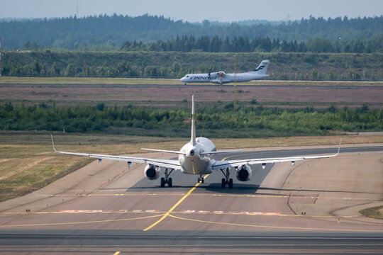 Airbus A321, operated by Finnair, taxiing at Helsinki airport. An ATR-72 taking off in the background
