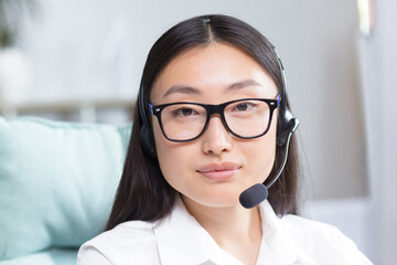 Close-up portrait photo of Asian female call center worker and tech support worker, looking at...