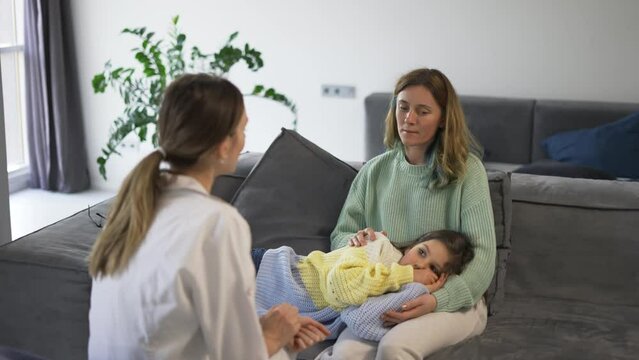 Mother with little daughter talking to health visitor at home