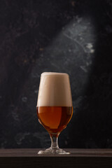 Tulip glass of beer on black background.