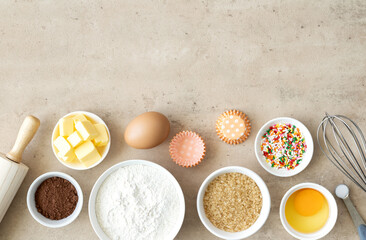 Baking cake ingredients. Cake ingredients. Baking ingredients: sugar, flour, butter, eggs, milk, rolling pin, baking powder, cocoa, utensils, whisk on a beige background. Top view, copy space.