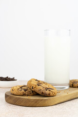 Chocolate chip cookies and a glass of fresh milk on a wooden board, on a white background. copy space.