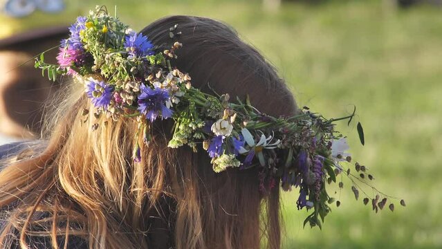 Wreath of flowers and oak leaves on the head. Celebration of the summer solstice in greenery. Midsummer celebration with oak wreath. Ligo holidays with weaving an oak wreath with your own hands.
