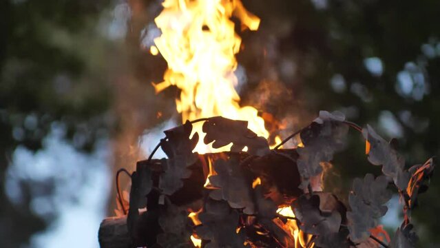 Crown on a pillar with fire. Close-up of a fire on a pole. A cinematographic picture. Soft focus on objects. Pagan bonfire festival in Latvia Summer night Ligo. Midsummer bonfire on a pole.