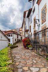 Typical street of Lastres, with stone houses and potted flowers on the balconies, Asturias.