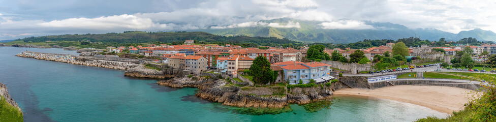 Fototapeta na wymiar Panoramic view of Llanes, with the Sablon beach, the breakwater of the cubes of memory, and the Cantabrian mountain range in the background, Asturias.