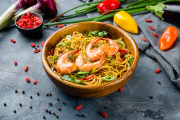 wok with shrimp, egg noodles with shrimps and vegetables on wooden bowl