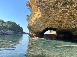 Naklejka premium Beautiful island in the sea bay with turquoise clear water. Scenic sea cave grotto. Paradise beach in sunny summer day.