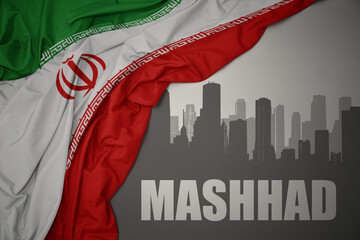 abstract silhouette of the city with text Mashhad near waving national flag of iran on a gray...