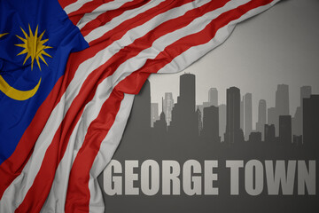 abstract silhouette of the city with text George Town near waving national flag of malaysia on a gray background.3D illustration