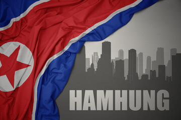 abstract silhouette of the city with text Hamhung near waving national flag of north korea on a gray background.3D illustration
