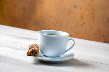 Cup of coffee with coffee beans on a wooden table. White cup with espresso coffee. Background for a coffee shop. Arabica.