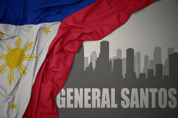 abstract silhouette of the city with text General Santos near waving national flag of philippines on a gray background.3D illustration