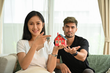 New house concept with happy young Asian couple holding small house model.