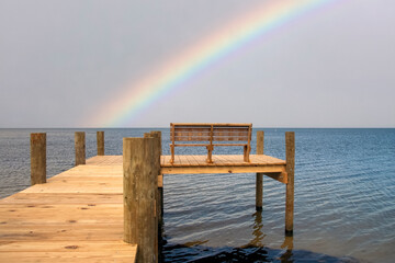 wooden pier on the beach with stormy rainbow