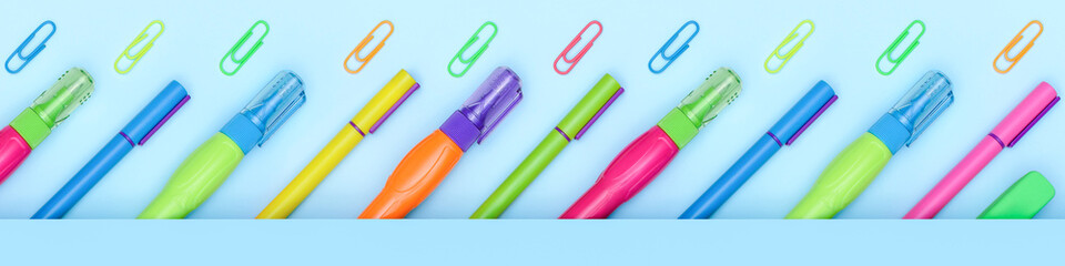 Multicolor bright school and office stationery items in a row on a blue background with copy space. Banner.