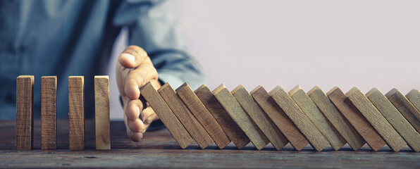 Hand prevent wooden block stacked concept of prevent collapse or crash of financial business and risk management or strategic planning and insurance.