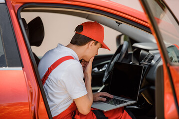 Car mechanic is using an laptop computer to check the car errors and problem and fix it. .