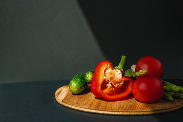 branches of fresh green asparagus, peppers, tomatoes and cucumbers on a wooden board, dark gray background, top view. Basic trend concept with copy space.