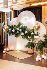 festive arch with white cake with berries, gold air balloons, white flowers, candles, monstera...