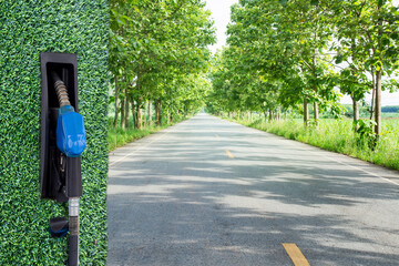  Green gasoline nozzle on  Both sides of the road are planted with street trees background. Refill...