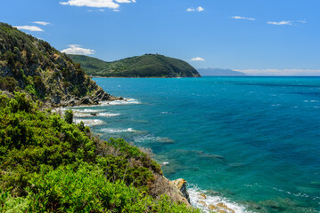 Felsküste von Barrati mit blauem Himmel und vereinzelten Wolken mit Blick auf Populonia