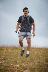 Swarthier type of man is running down a gravel hill, checking his every step to avoid injury. Active athlete runs over challenging terrain to improve fitness, coordination and precision of movement