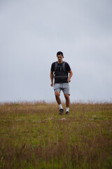 Obraz premium Swarthier type of man is running down a gravel hill, checking his every step to avoid injury. Active athlete runs over challenging terrain to improve fitness, coordination and precision of movement