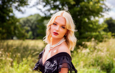 Portrait of a beautiful blond lady wearing a topless black dress and pearls