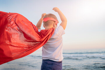 child boy in a superhero costume with a red cape