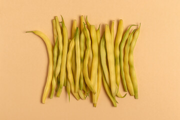 Yellow string beans on a beige background. Top view.