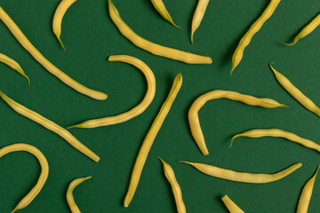 Yellow string beans on a green background. Top view.
