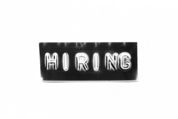 Black color banner that have embossed letter with word hiring on white paper background