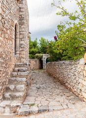 Greece. Mani Laconia, Peloponnese. Narrow path, stonewall building, rocky door with arch, nature.