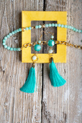 beautiful handmade  turquoise  jewelry with natural gems in yellow box around old style wooden background. close up. fashion concept