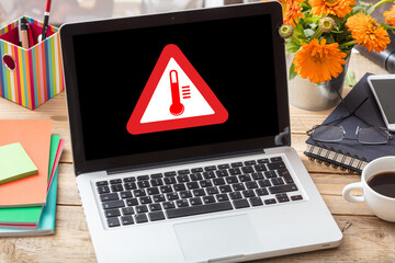 High temperature warning sign on a laptop screen.  Computer overheat, overload, hot weather danger