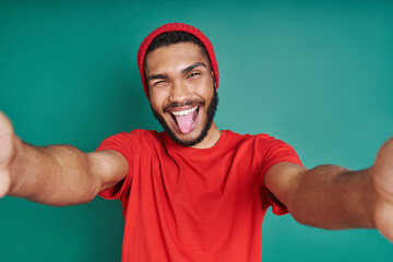 Playful African man stretching out hands while standing against green background