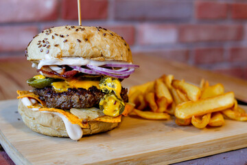 Burger w artystycznej kompozycji z frytkami i batatami oraz cebulą pieczarkami. Burgerownia - zdjęcie świeżego, apetycznego burgera